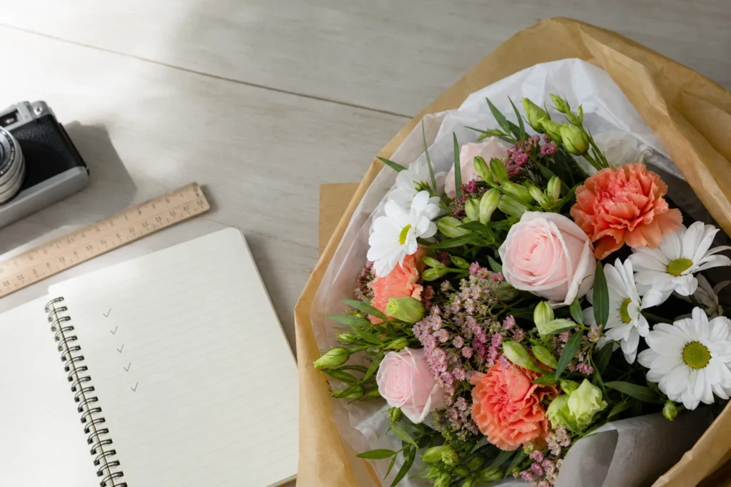 Frisch gelieferter Blumenstrauß auf einem Prüftisch mit Kamera und Notizen